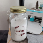 Glas mit Aufschrift "Zucker", Plotter im Hintergrund